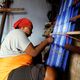 A Nigerian woman, using a local weaving tool to make traditional attire.